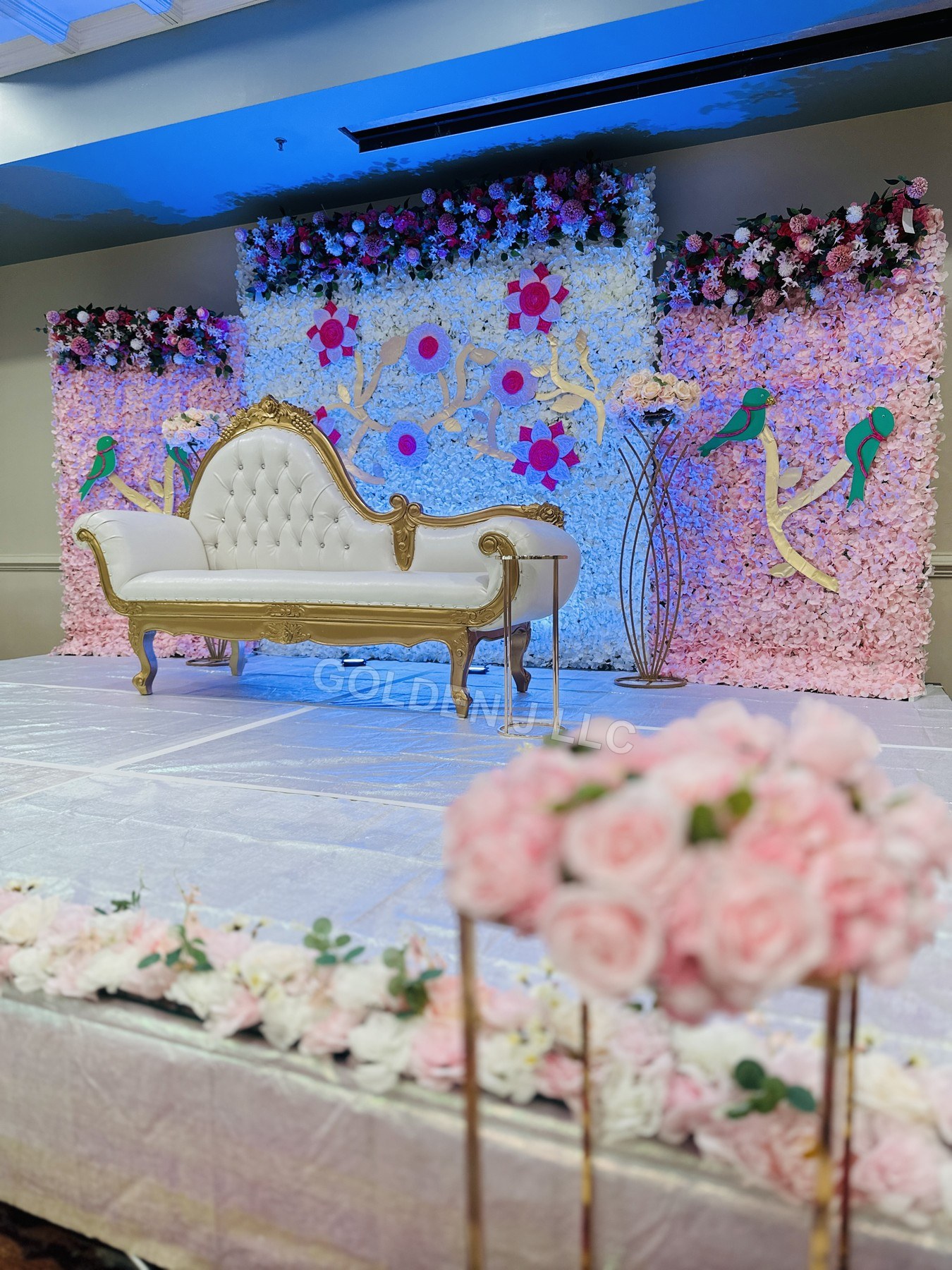 Golden J LLC floral event backdrop with a white and gold chaise lounge