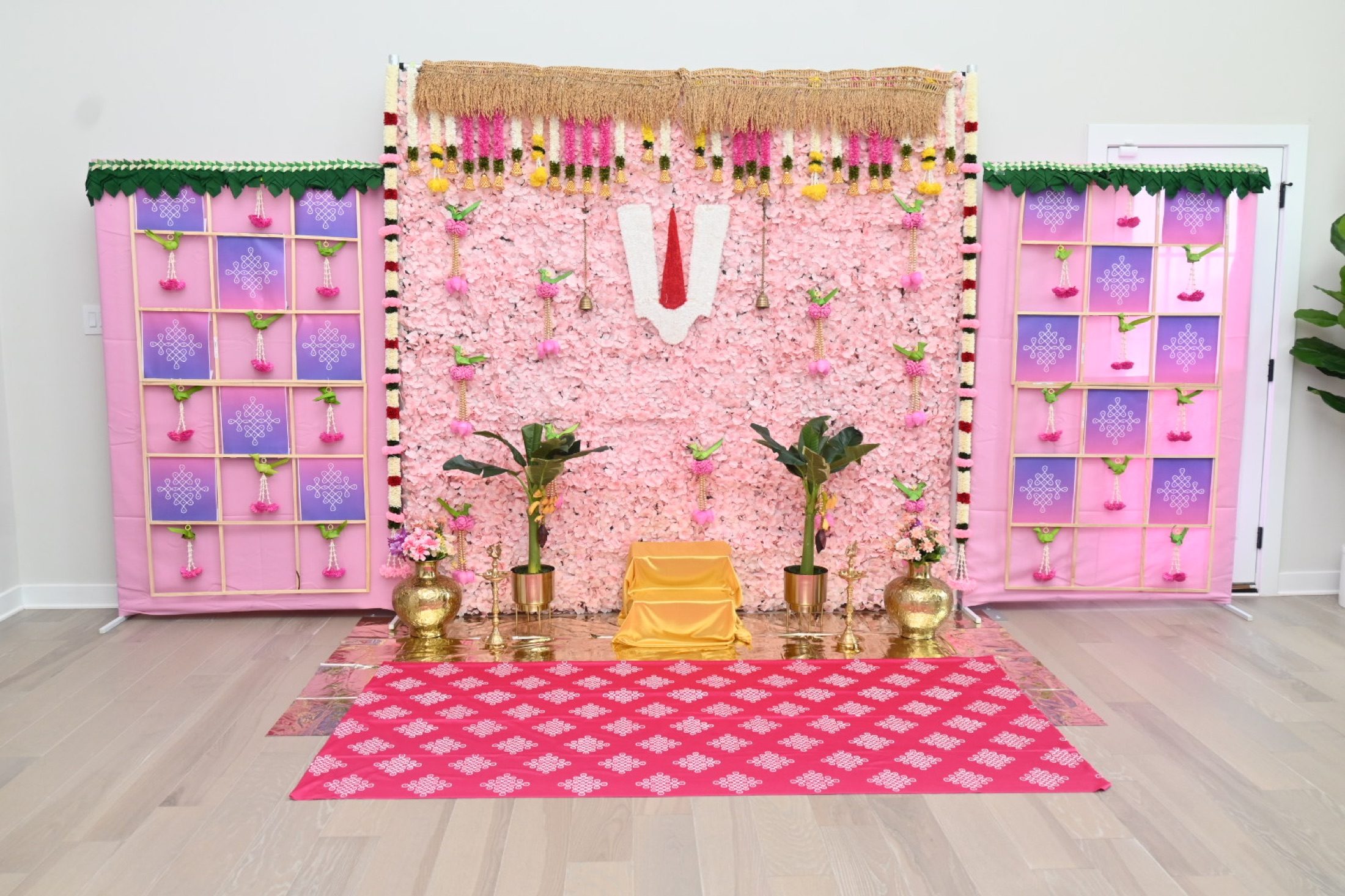 Pink traditional floral ceremony backdrop with decorative panels and brass accents