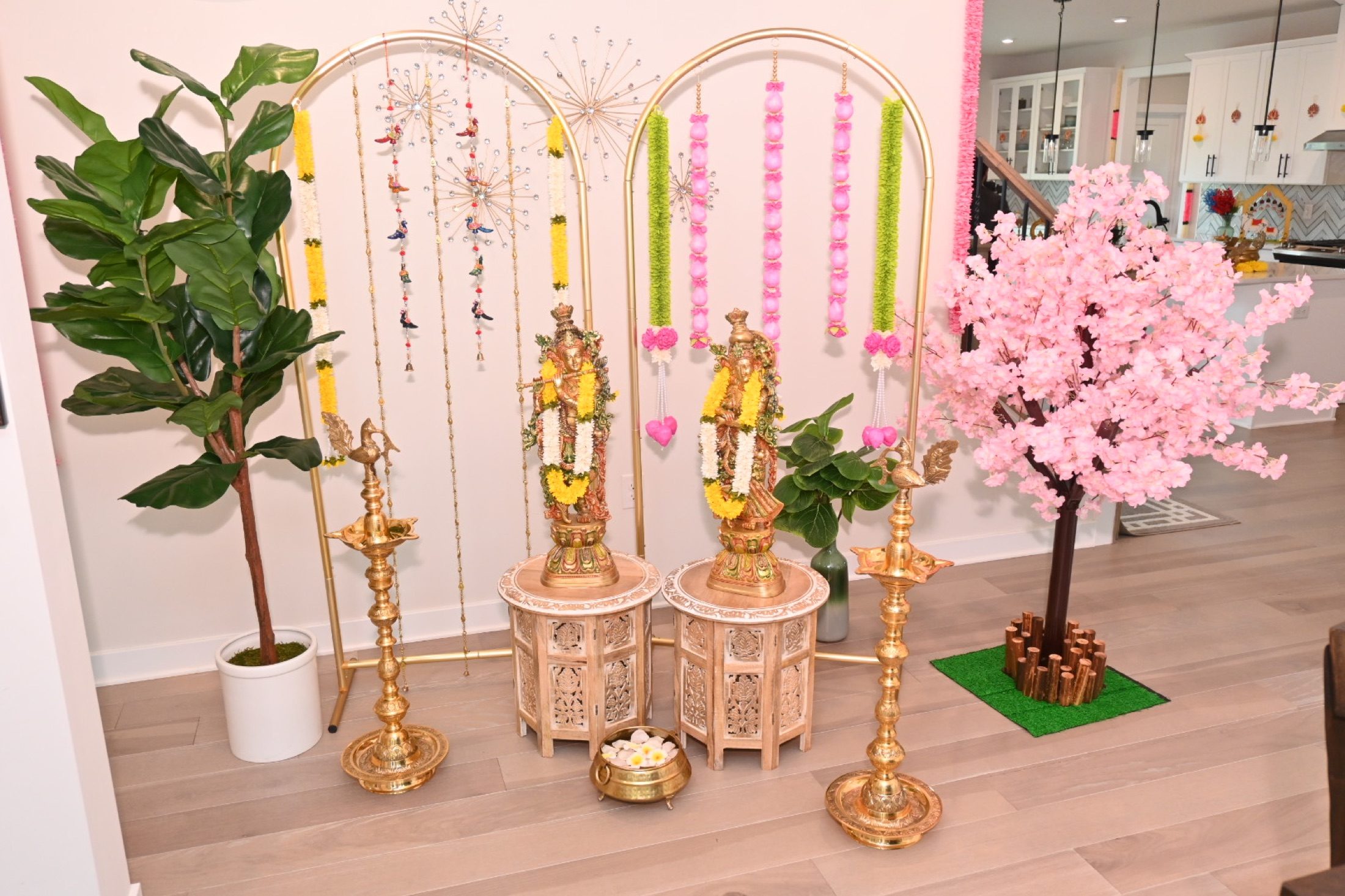 Traditional ceremonial display with gold arches, statues, florals, and brass lamps