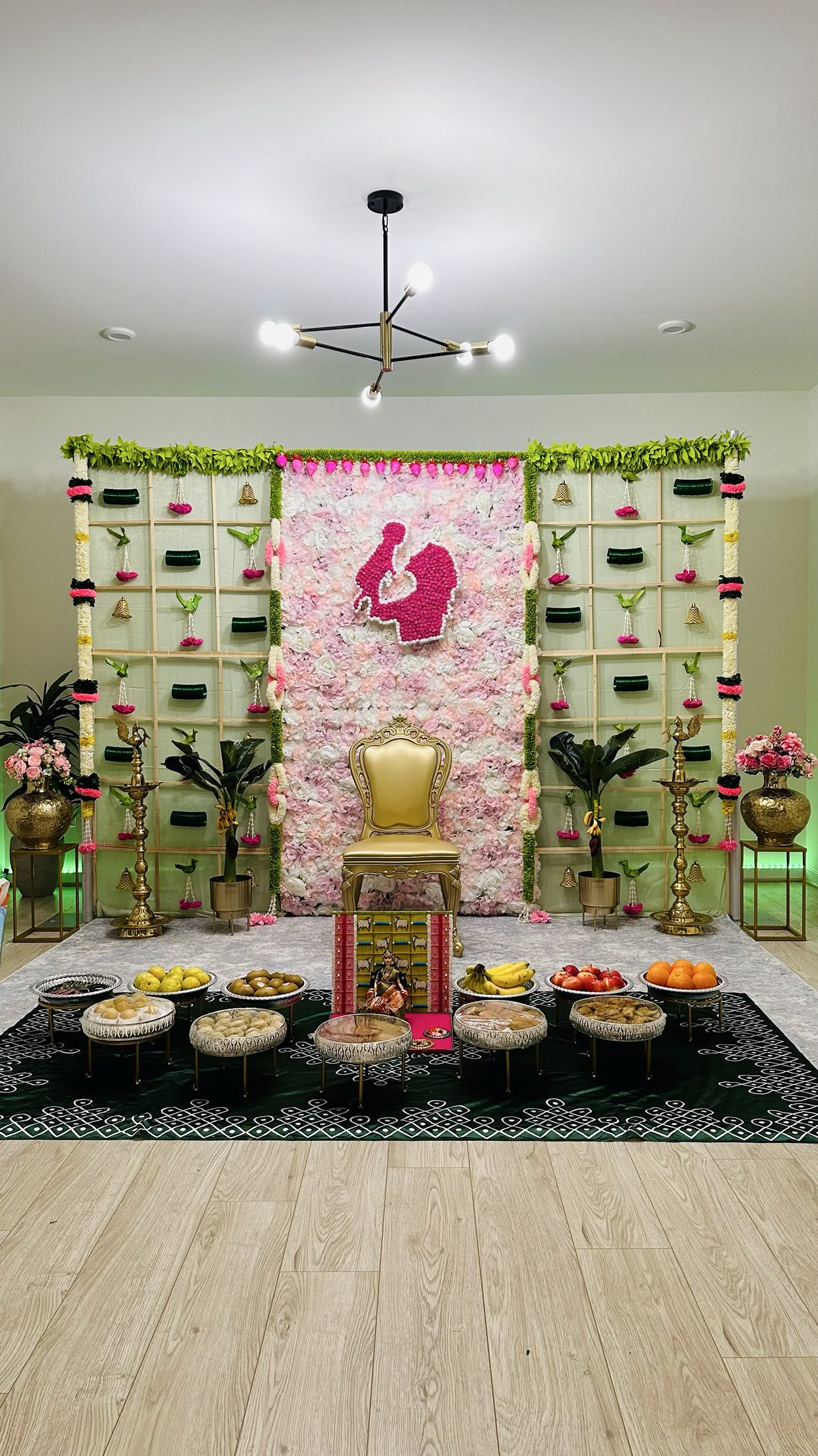 Pink and green traditional ceremony backdrop with a gold chair and floral details