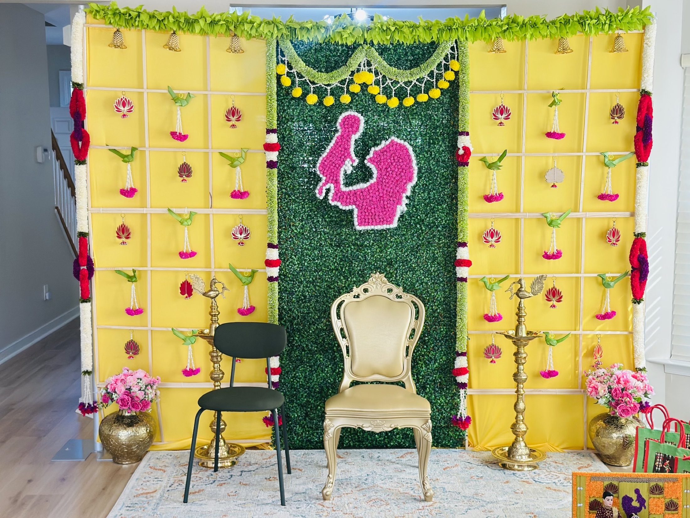 Yellow and green traditional ceremony backdrop with floral artwork and brass lamps