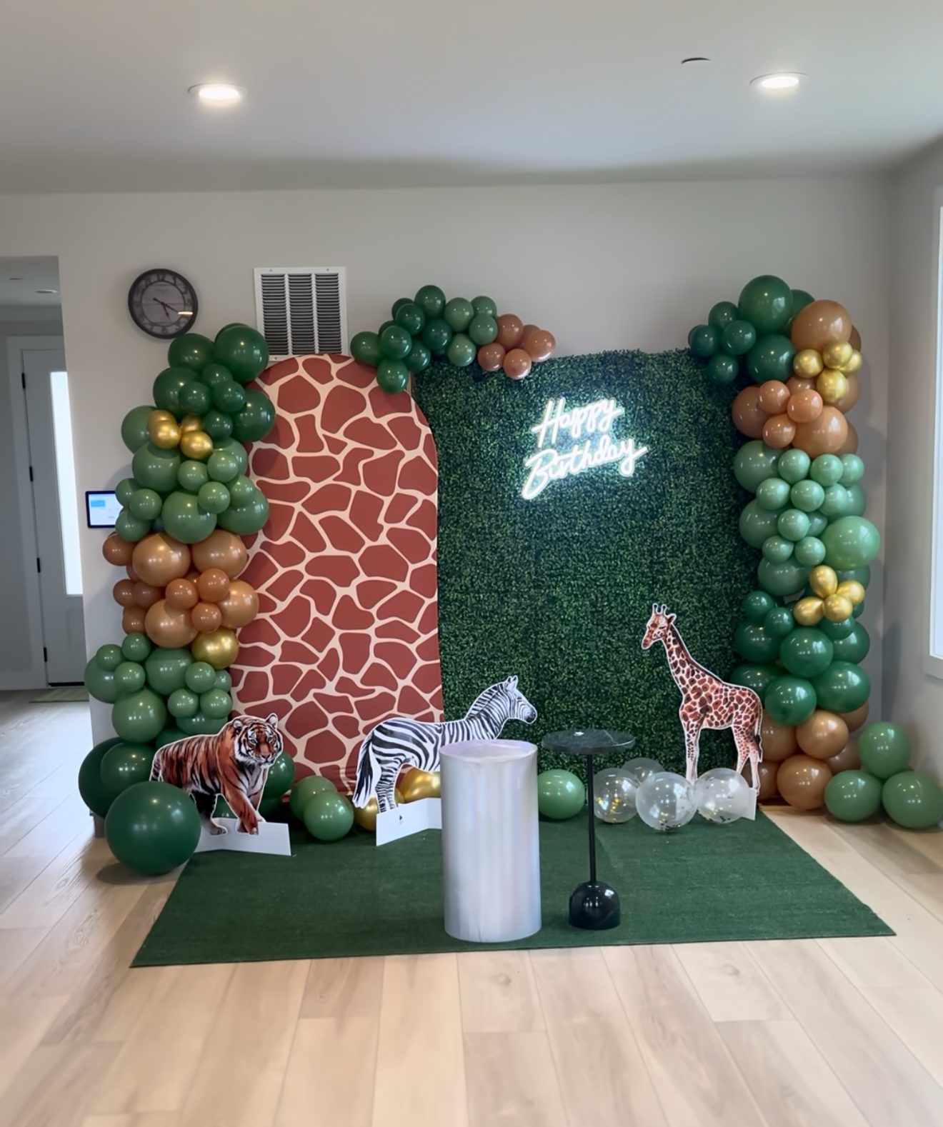Safari-themed birthday backdrop with green balloons and animal accents