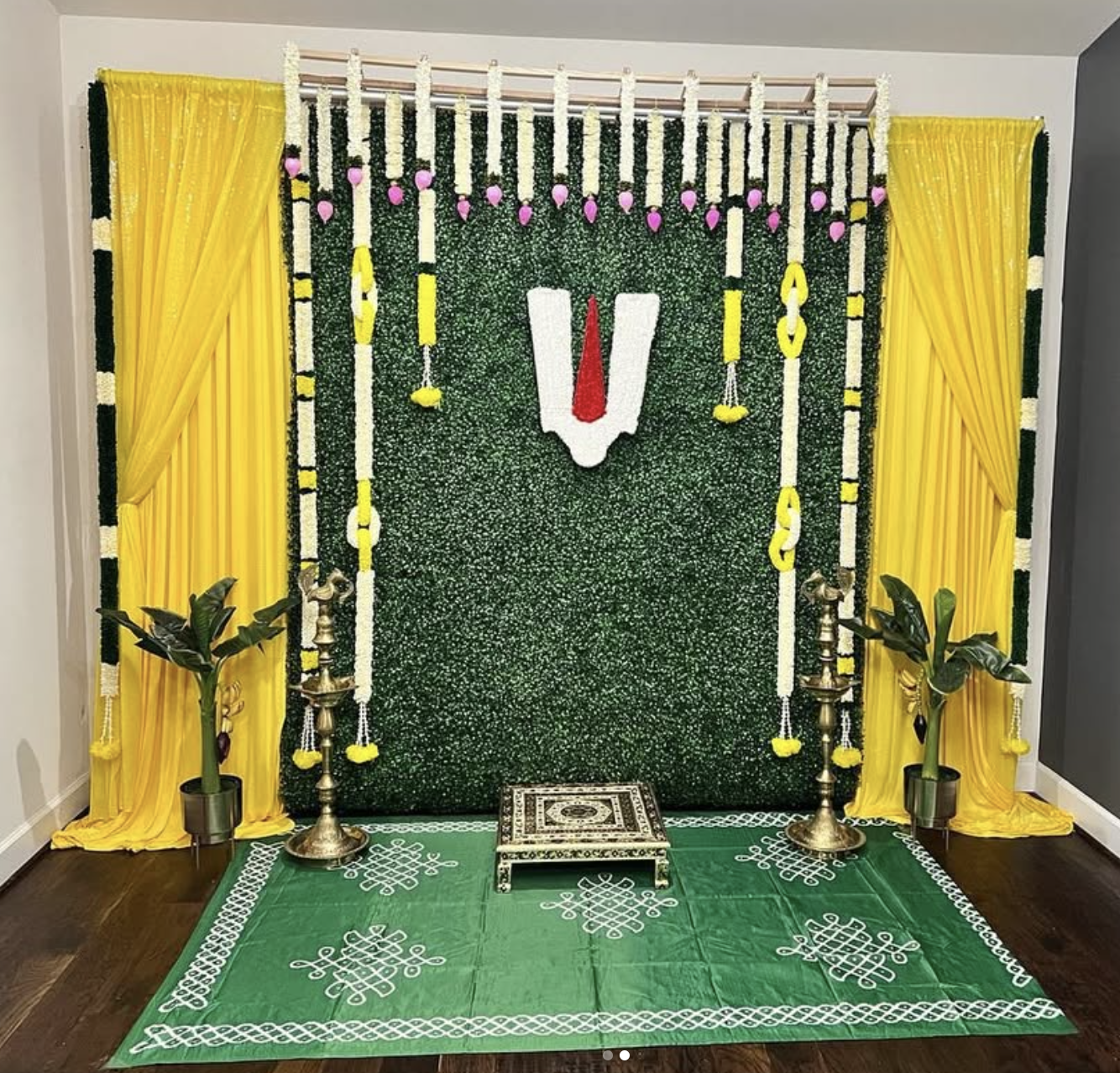 Green and gold traditional ceremony backdrop with floral garlands
