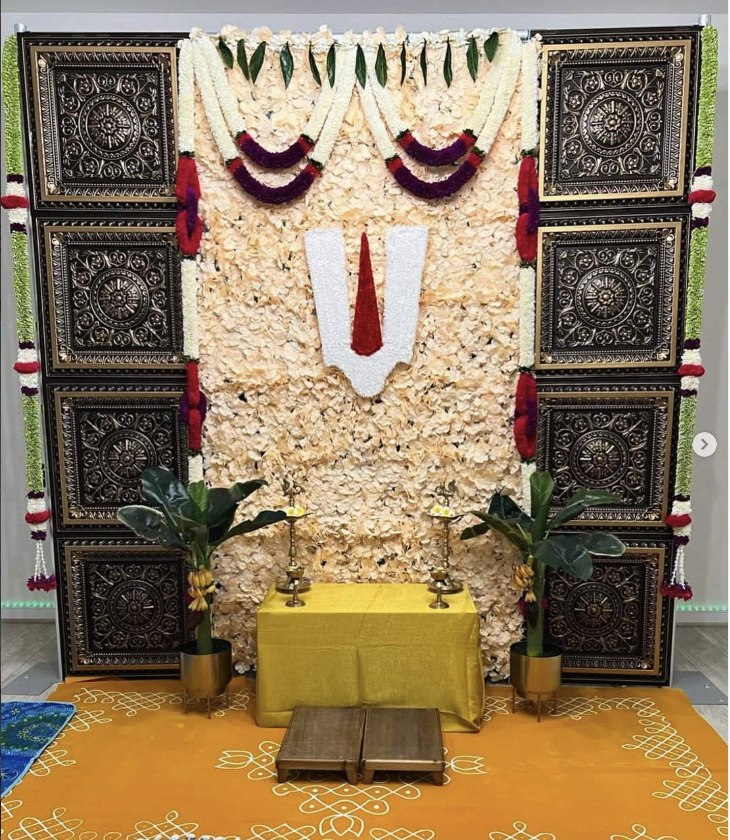 Traditional floral ceremony backdrop with carved panels and brass accents
