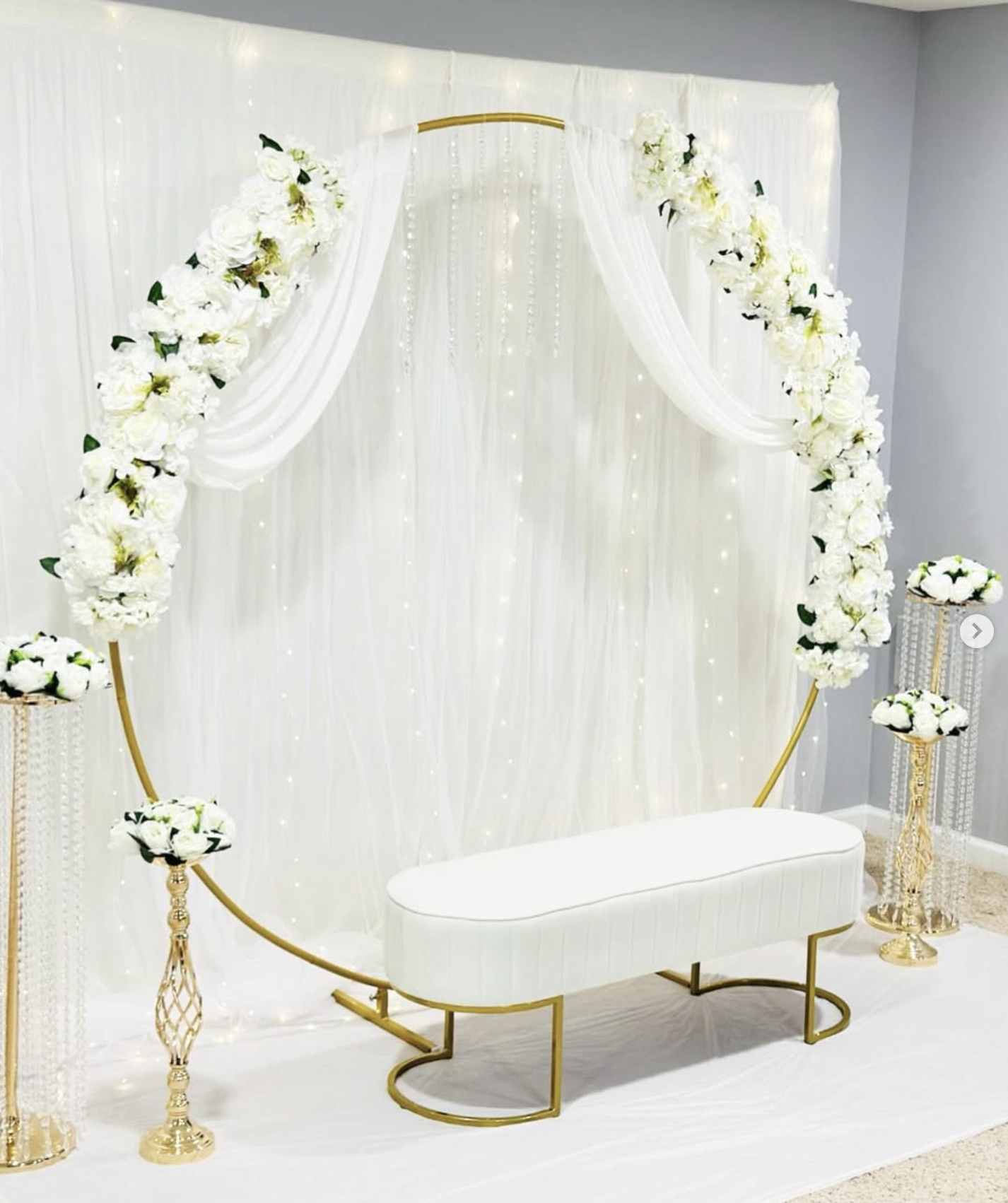 Elegant white and gold floral ceremony setting with a curved bench